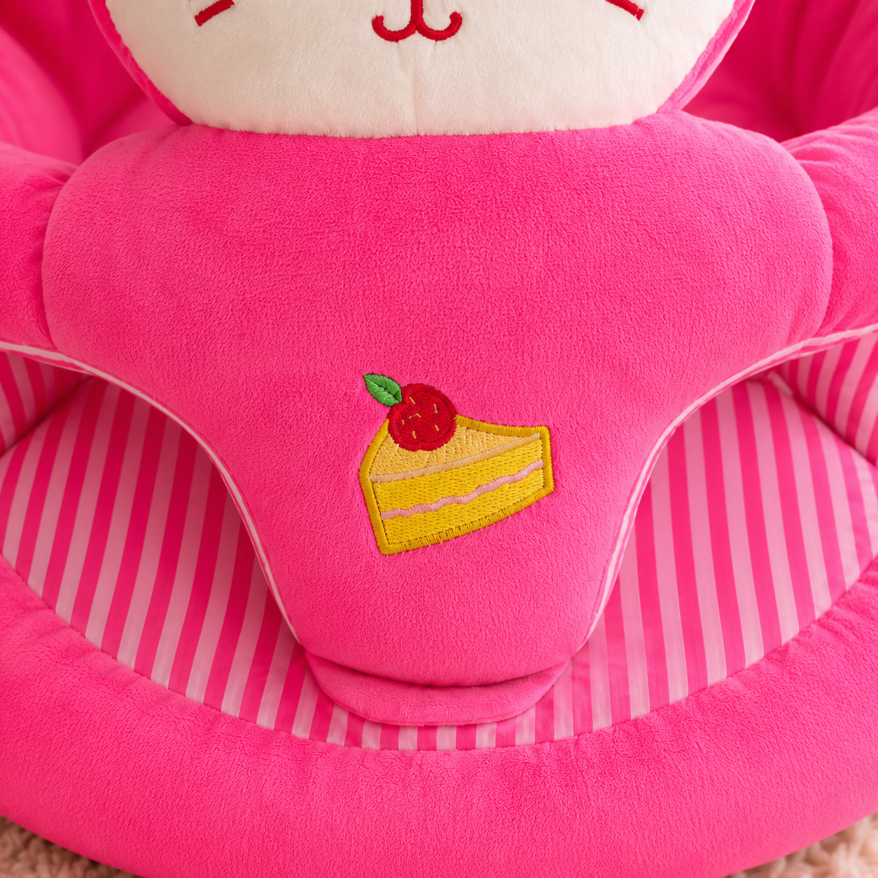 Pink plush toy with a slice of cake patch on a striped background