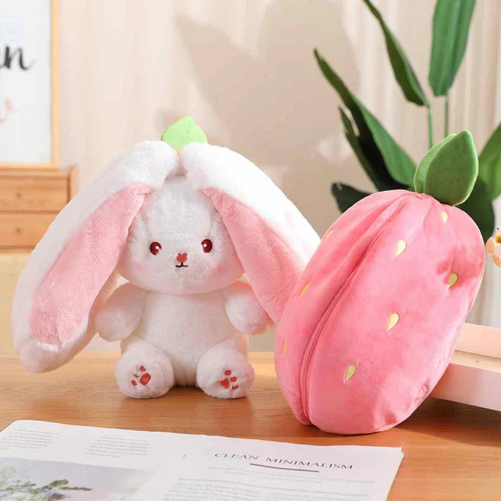 Plush bunny toy with a pink macaron-shaped case on a wooden surface.