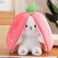 Plush toy shaped like a strawberry with a white rabbit inside, on a wooden surface.